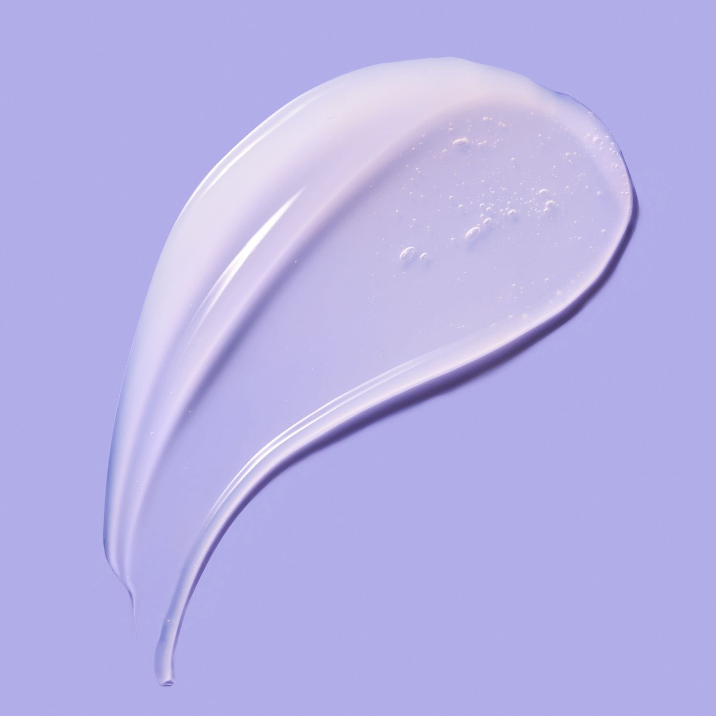 Smooth swirl of skincare product, spread across a purple background.