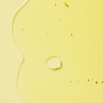 A smooth oil with droplets dispersed on a yellow background.