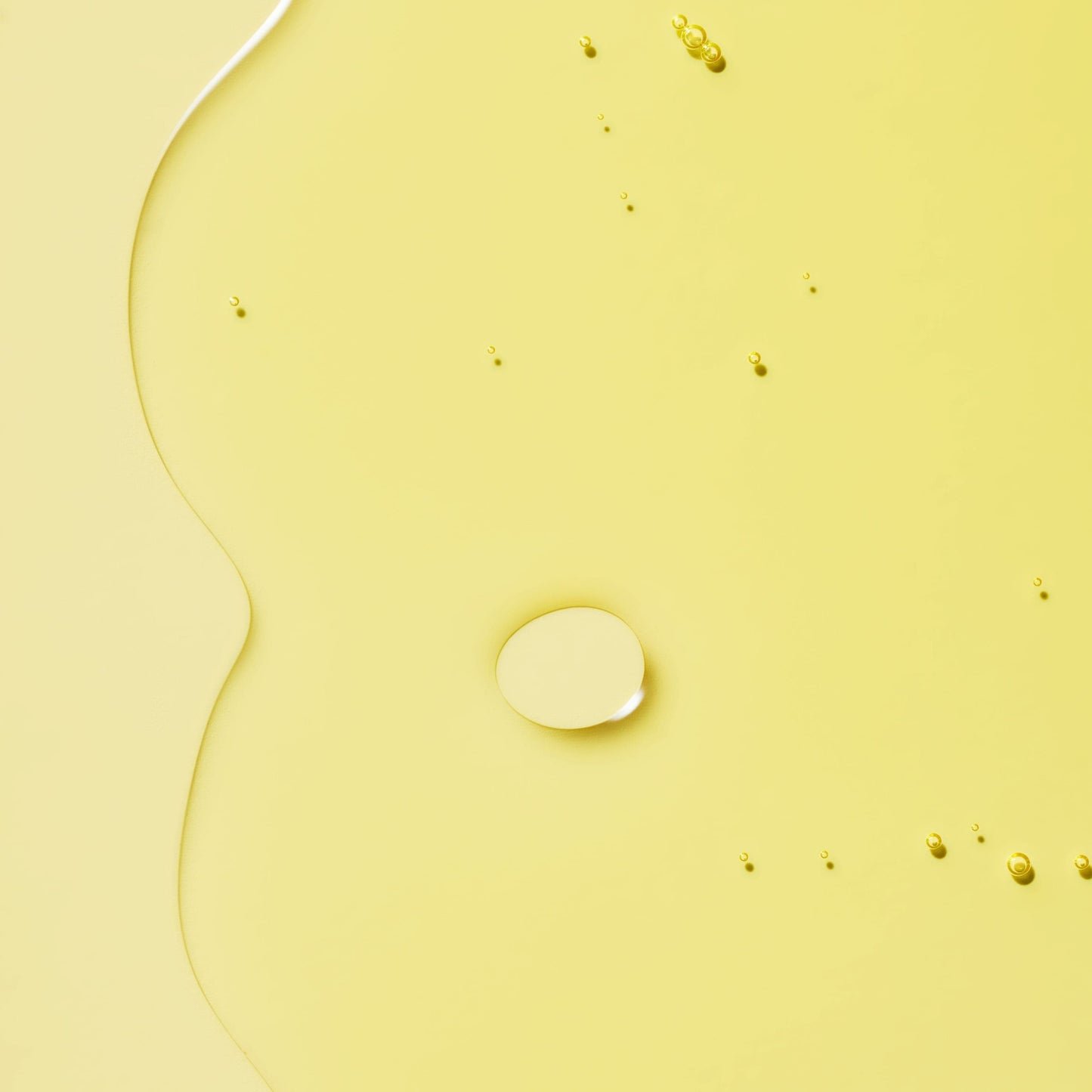 A smooth oil with droplets dispersed on a yellow background.