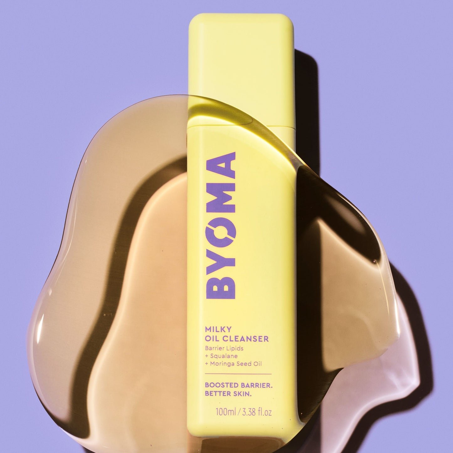 A bottle of BYOMA Milky Oil Cleanser placed on top of a smooth yellow oil surface.