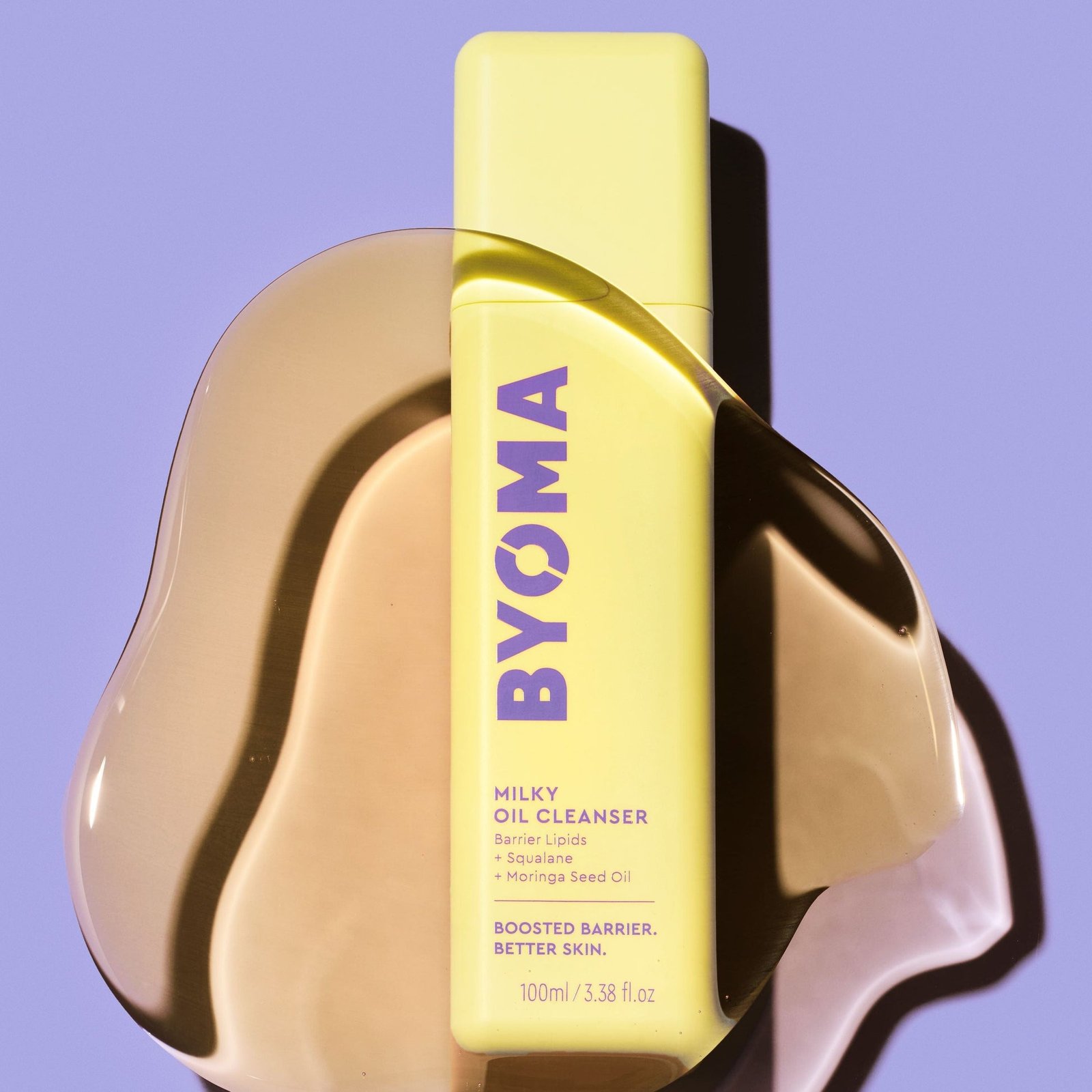 A bottle of BYOMA Milky Oil Cleanser placed on top of a smooth yellow oil surface.