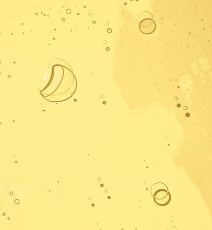 A smooth, golden skincare oil texture with bubbles.