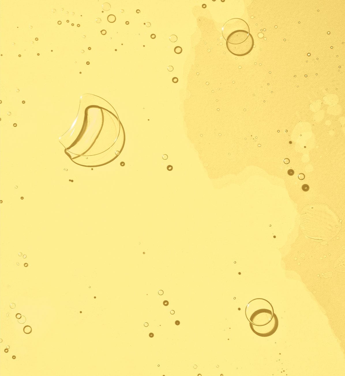 A smooth, golden skincare oil texture with bubbles.