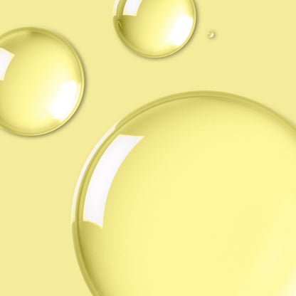 Close-up of translucent skincare oil droplets on a yellow background. 