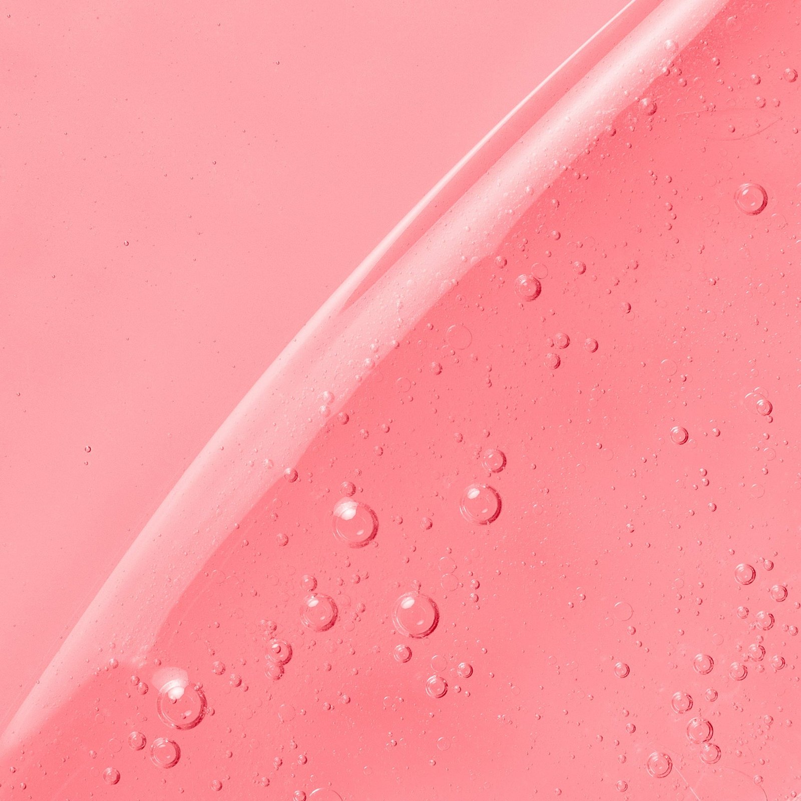 A pink gel-like skincare product with tiny bubbles, creating a glossy appearance.