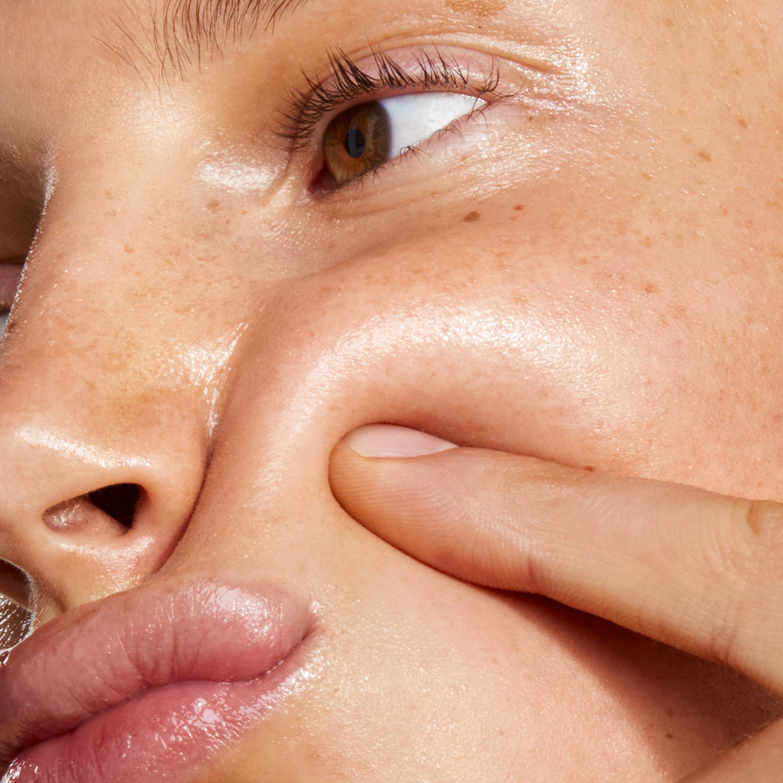 Close-up of a person gently pressing their cheek with a finger.