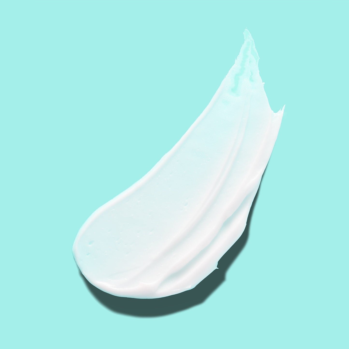 A creamy white skincare product smeared against a teal background.