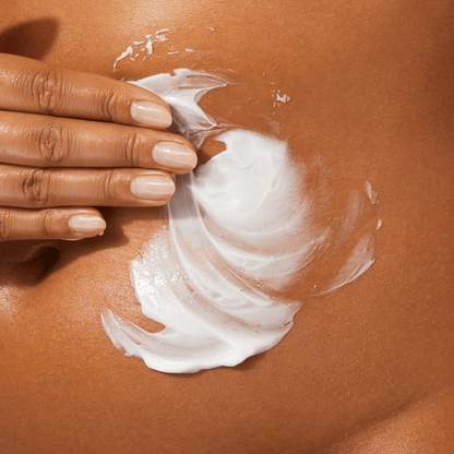 A creamy white body lotion being applied to the stomach.