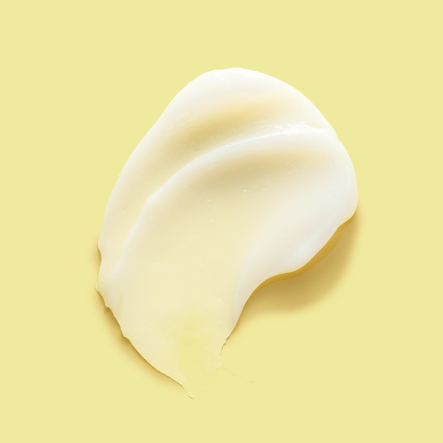 A smooth, creamy swatch of yellow-toned body lotion on a matching yellow background.