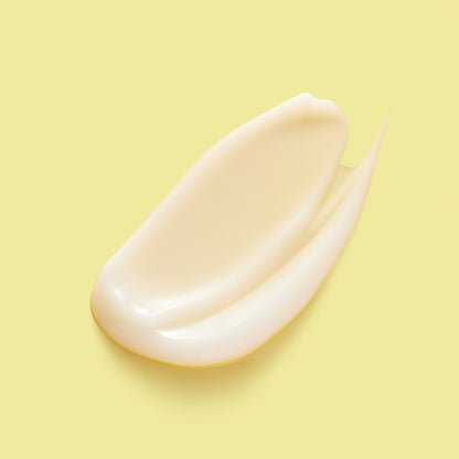 A creamy white skincare product smeared against a yellow background.