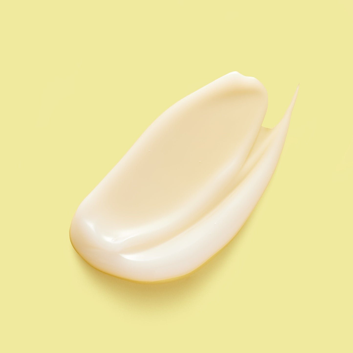 A creamy white skincare product smeared against a yellow background.