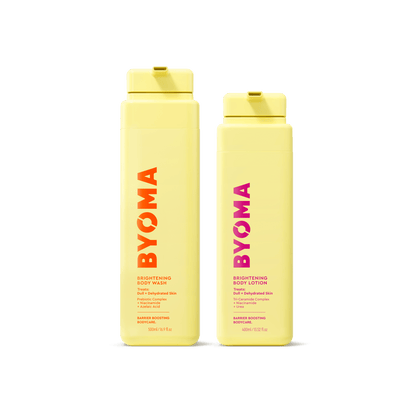 Two yellow BYOMA bottles on a transparent background. Left: Brightening Body Wash with orange-red text; right: Brightening Body Lotion with pink text. Both are upright.