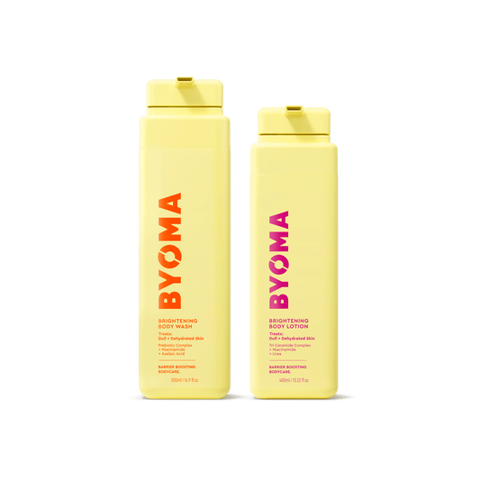 Two yellow BYOMA bottles on a transparent background. Left: Brightening Body Wash with orange-red text; right: Brightening Body Lotion with pink text. Both are upright.
