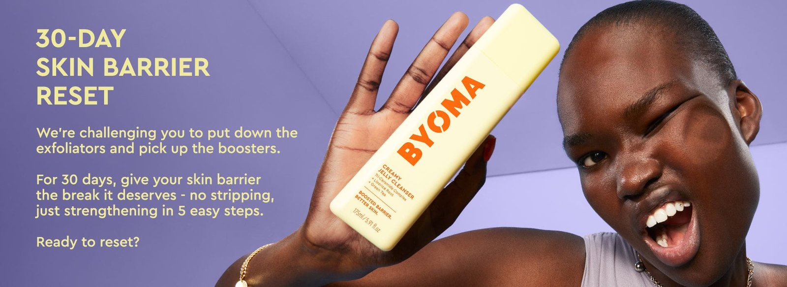 A smiling woman with dark skin and short hair, whose face is pressed against an invisible barrier, holds a yellow BYOMA product labeled "Creamy Jelly Cleanser." Text on the left side reads "30-DAY SKIN BARRIER RESET" and explains a 30-day challenge to avoid exfoliators and use barrier-boosting skincare. Background is lavender-purple.